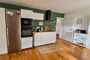 A compact kitchen with a refrigerator, oven, microwave, and a small countertop. - Dreamy Roof Terrace Eifelgluck (Pelm)