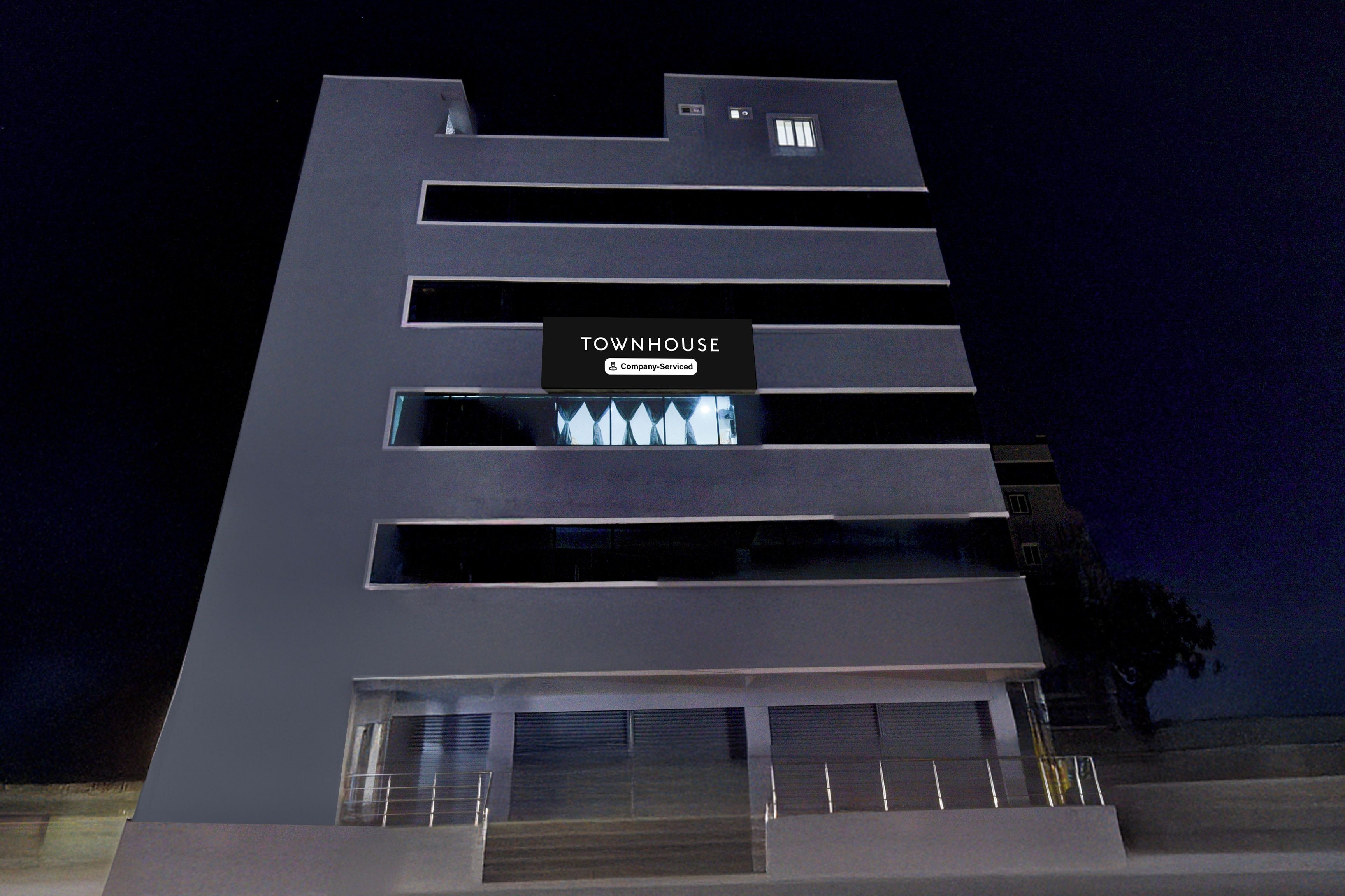 Un edificio moderno con un letrero que dice 'TOWNHOUSE' y un logotipo de la empresa.