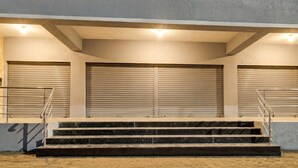 A set of outdoor stairs leading to a building with closed roller shutters.