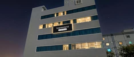 En bygning med flere etager, med skilt der står 'TOWNHOUSE' og en etiket for virksomheds service.