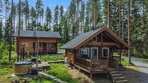 Una cabaña con terraza, rodeada de bosque.