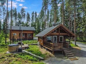 Una cabaña con terraza, rodeada de bosque.