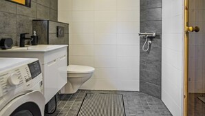 Baño pequeño con inodoro, lavadora y zona de ducha.
