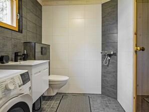 Baño pequeño con inodoro, lavadora y zona de ducha.