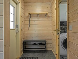 A wooden sauna room with a bench, a towel rack, and a washing machine in the corner.