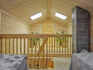 Interior de madera con techo alto, dos tragaluces, una puerta de madera y una chimenea de piedra.