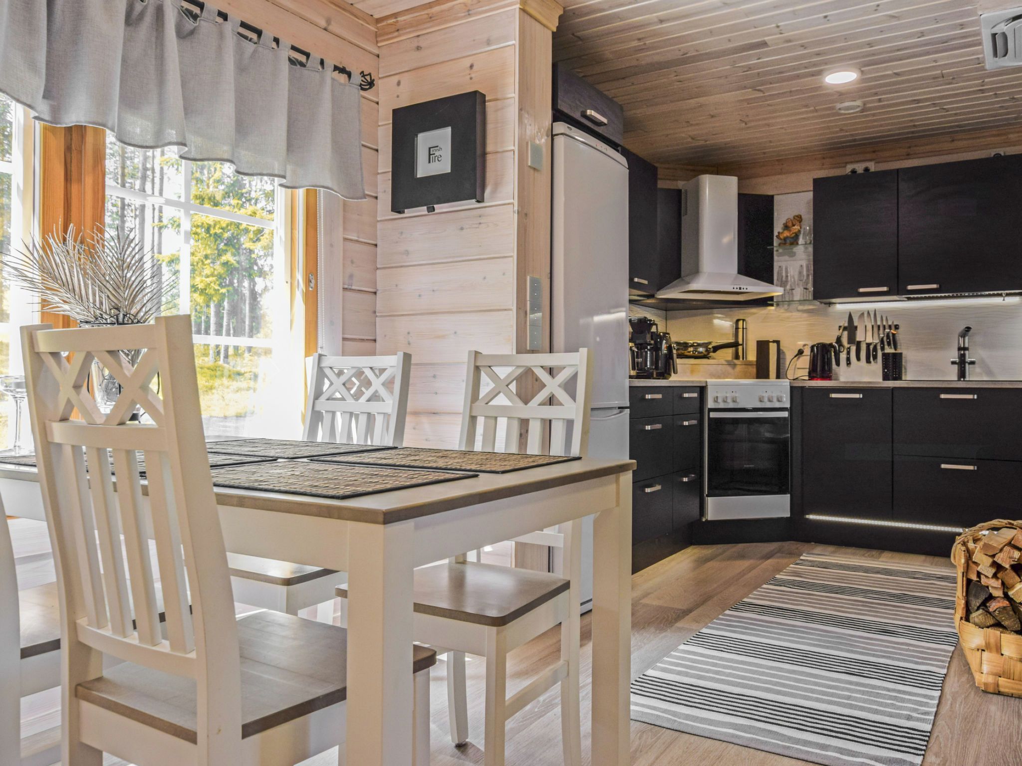 Eine moderne Küche mit Essbereich, ausgestattet mit Holzvertäfelung, einem Herd, einem Backofen und einem Kühlschrank.