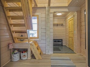 A wooden interior with a lofted sleeping area, a bench, and a window.