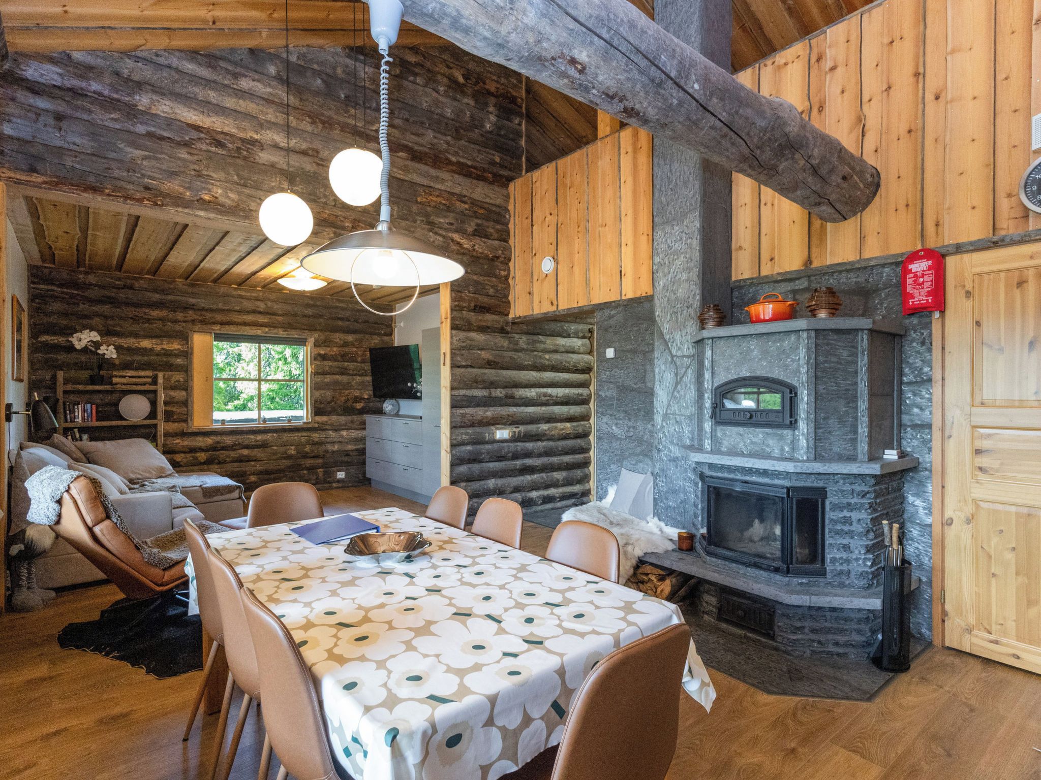 Interior rústico de una cabaña con una mesa de comedor, sillas, chimenea y paredes de madera.