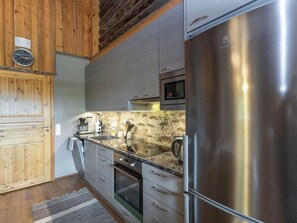 A modern kitchen with stainless steel appliances, grey cabinetry, and a wooden ceiling. - Honka 1a by Interhome (Kuusamo)