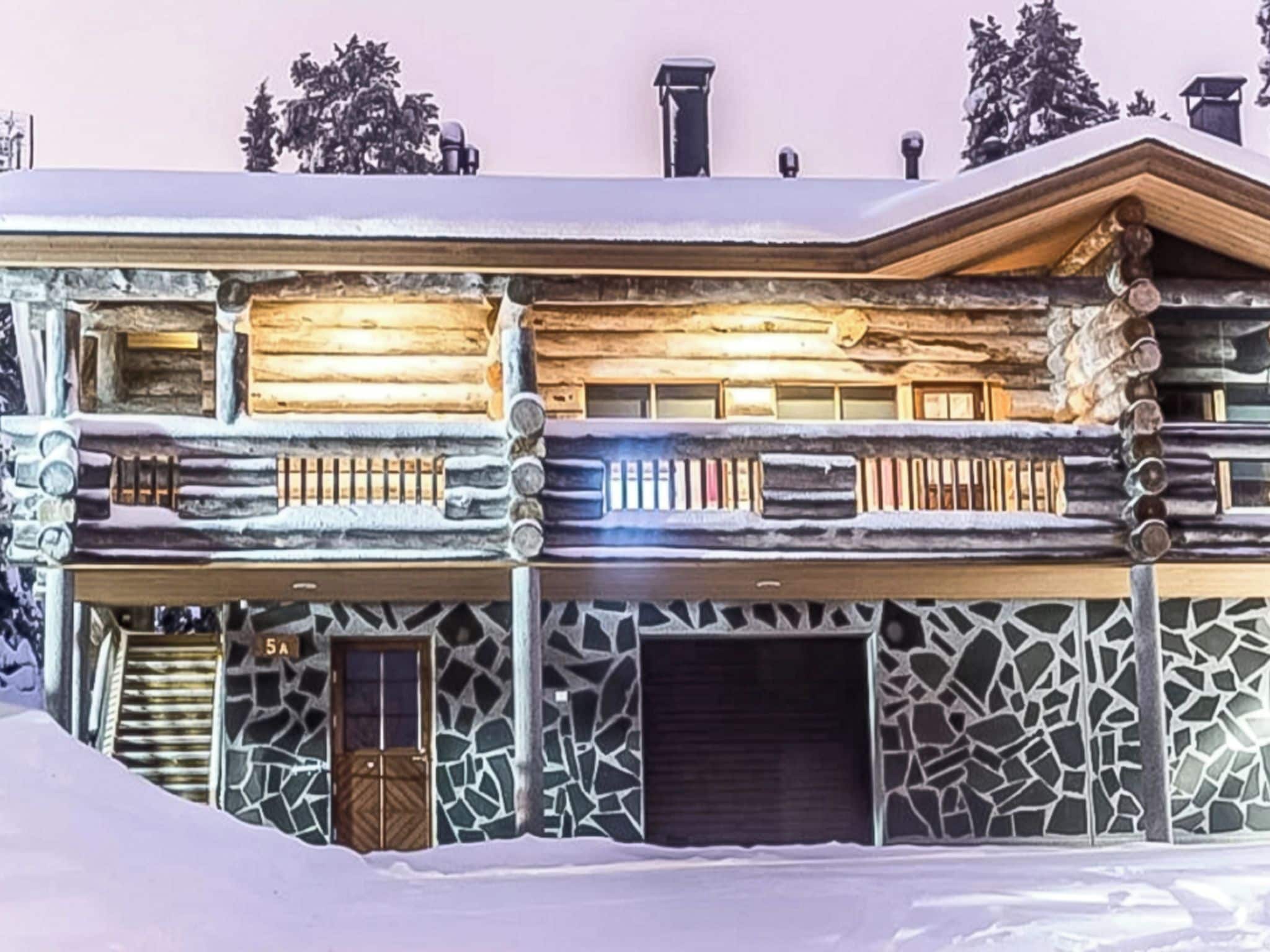 A log cabin with a stone facade, multiple balconies, and a snow-covered roof.