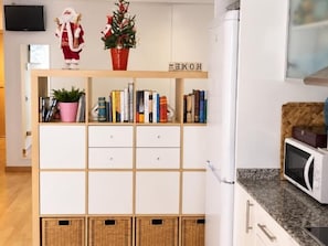 A kitchen with a white cabinet, a microwave, and a television on the wall. - Winahost Loft el Rincón de Sants (Barcelona)