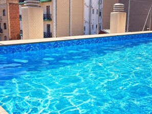 Une piscine à l’eau d’un bleu cristallin, entourée d’immeubles.