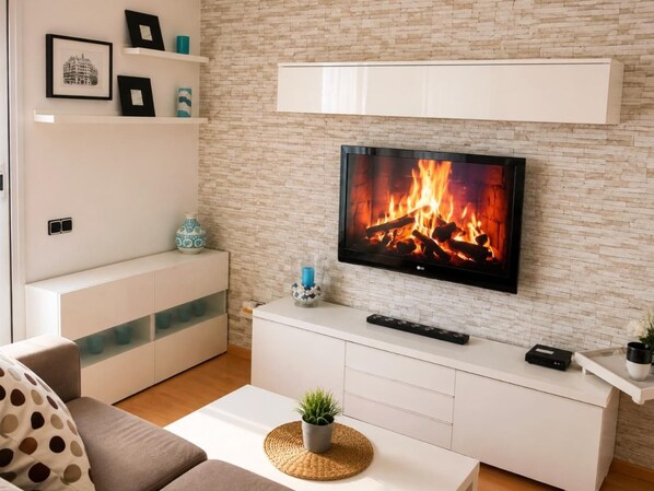 Un salon moderne avec un téléviseur à écran plat fixé à un mur en briques, un meuble de rangement blanc et un canapé agrémenté d’un coussin à pois.