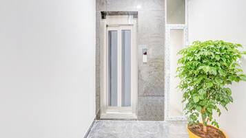 Interior moderno com piso de mármore, planta em vaso e porta com painel de vidro.