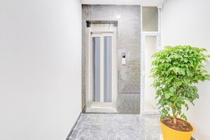 A modern interior with a marble floor, a potted plant, and a door with a glass panel.