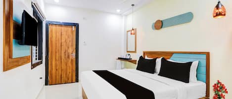 A hotel room with a bed, a television, a ceiling fan, and a nightstand with a vase of flowers.