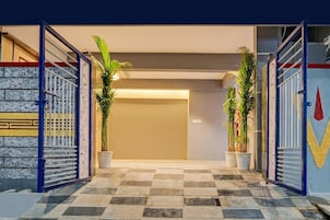 A hotel entrance with a checkered floor, a metal gate, and potted plants.