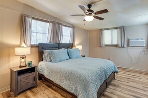 A bedroom with a bed, nightstands, a ceiling fan, and an air conditioning unit. - Cedar Creek Lake House! Beautiful Lake Views! (Mabank)