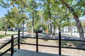Een woonwijk met een houten terras, bomen en huizen op de achtergrond.