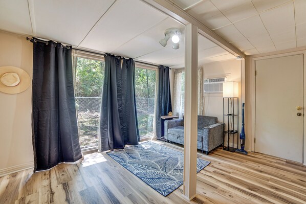 Een kamer met een groot raam, een bank, een tafel en een lamp.