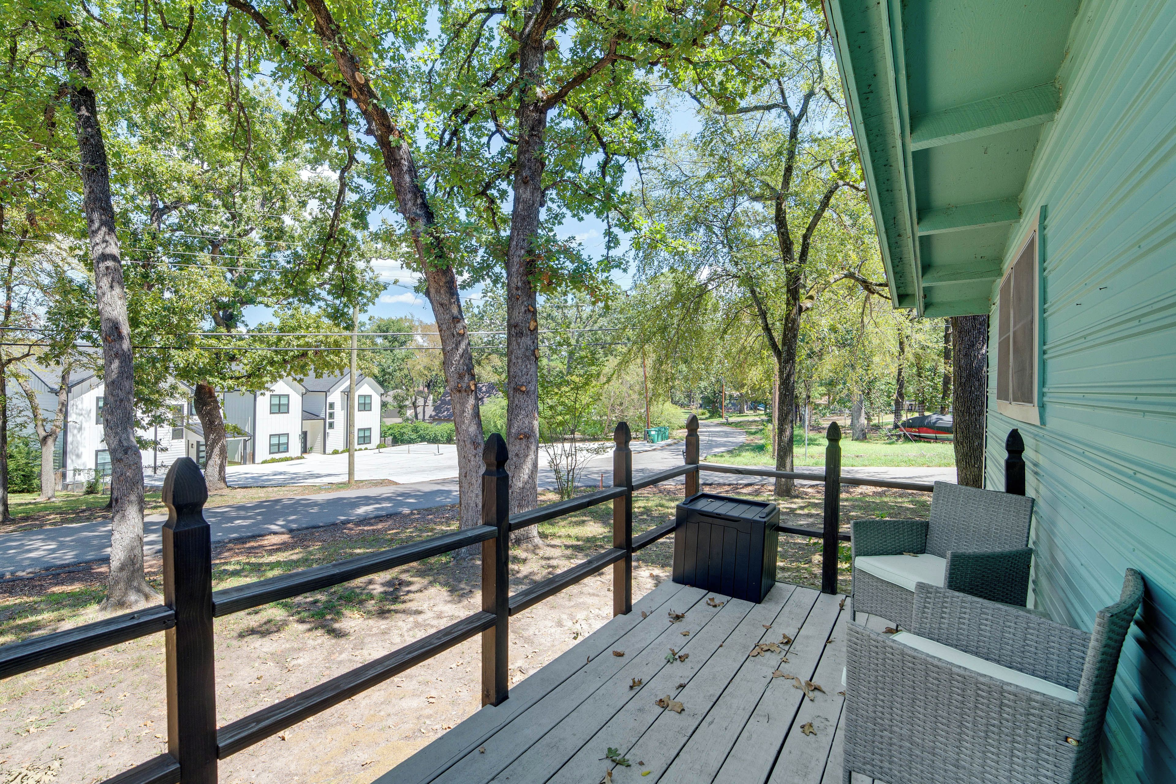 A wooden deck with a railing, a wicker sofa, and a trash bin.