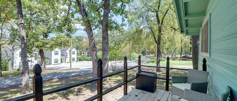 A wooden deck with a railing, a wicker sofa, and a trash bin.