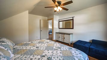 A bedroom with a bed, a ceiling fan, a dresser, and a blue chair.