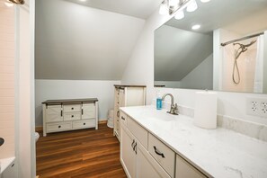 Un bagno moderno con un mobile vanitario bianco, uno specchio grande e uno spazio doccia.