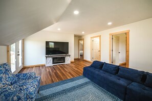 A spacious living area with a flat-screen TV, a blue sofa, and a patterned rug.