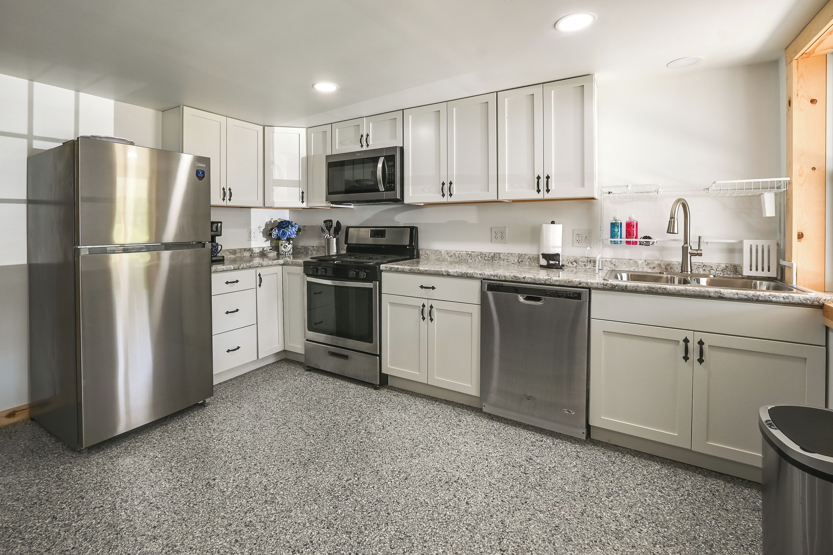 A modern kitchen with stainless steel appliances, white cabinetry, and granite countertops.