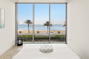 A hotel room with a large window offering a view of the sea and palm trees. - Muraba Residences - 103-n 2BD (Dubai)