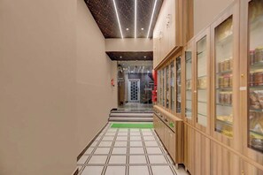 Un pasillo con piso de baldosas, armarios de madera con puertas de vidrio e iluminación empotrada en el techo.