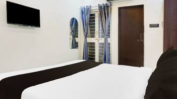 A room with a bed, a television mounted on the wall, and a door with a window.
