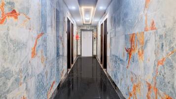 A corridor with marble walls and a black floor, leading to a door with a number sign.