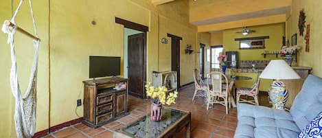Una sala de estar con un sofá, una mesa de centro, un televisor y un comedor con sillas y una mesa.