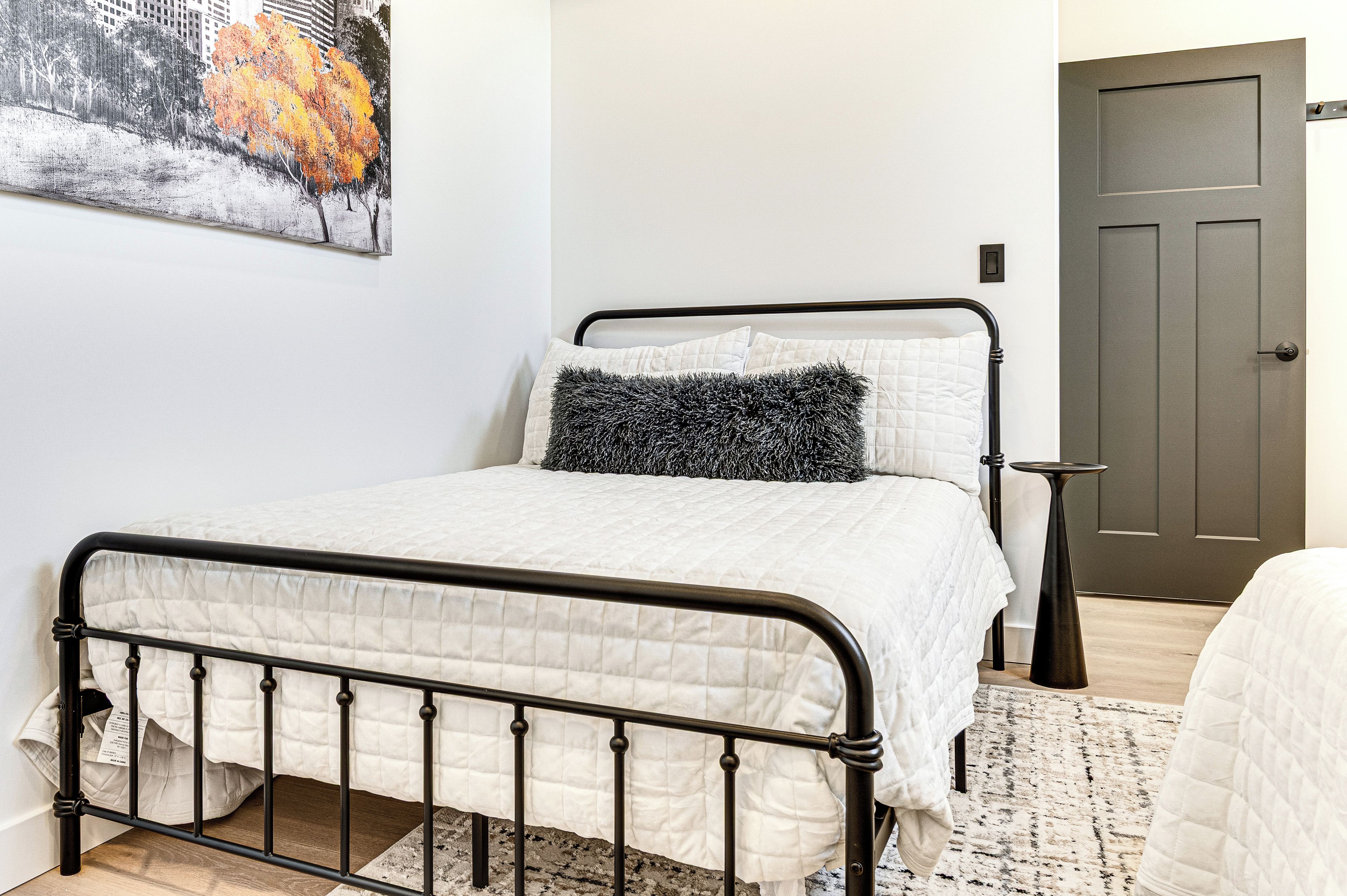 Un dormitorio con una cama, una puerta y un cuadro en la pared.