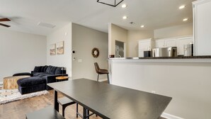 Un salon moderne avec un canapé foncé, une table basse en bois et une table à manger.