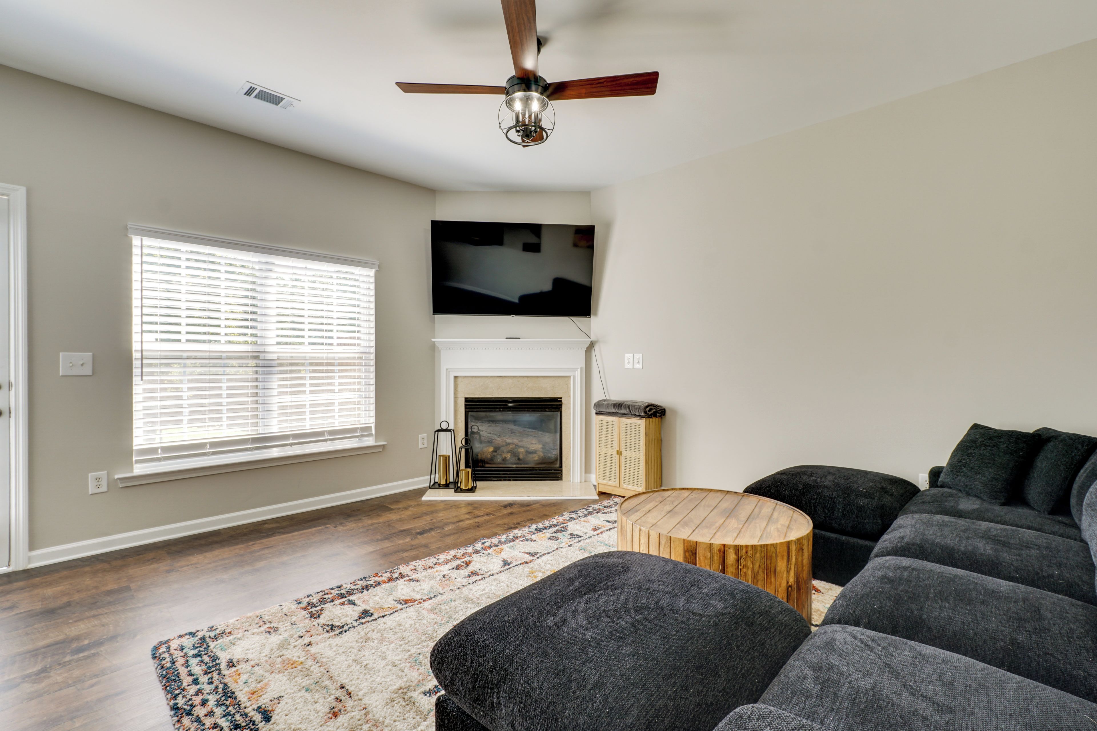 A living room with a fireplace, a ceiling fan, a television, and a sofa.