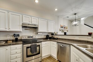 A kitchen with white cabinets, a stainless steel stove, a dishwasher, and a granite countertop.