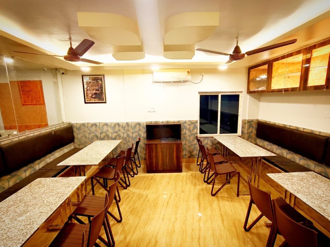 Un restaurante con cabinas y mesas, ventiladores de techo y un televisor.