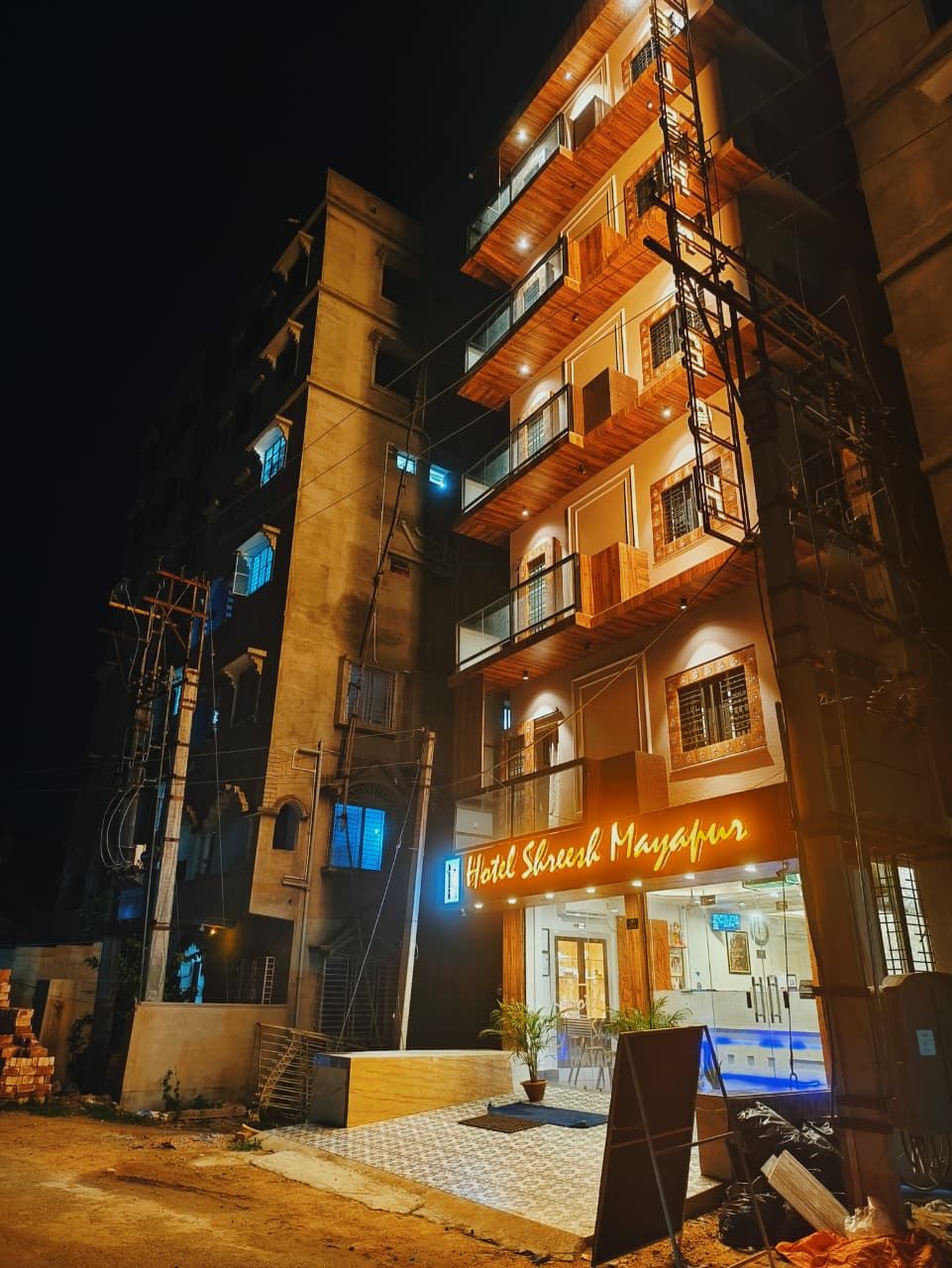 Un edificio de varios pisos con un letrero de neón que dice 'Hotel Shree Marathir'.