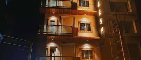 Un hotel de diversos pisos amb un rètol de neó, balcons i una entrada enrajolada.