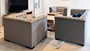 Una sala de estar moderna con un televisor de pantalla plana, dos sofás grises, una mesa de centro y una lámpara de pie.