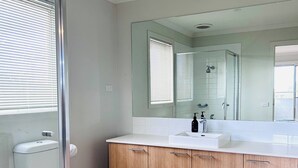 Un baño moderno con inodoro, cabina de ducha y tocador con espejo.