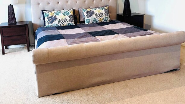 Un dormitorio con una cama grande, dos mesitas de noche y una lámpara en el techo.