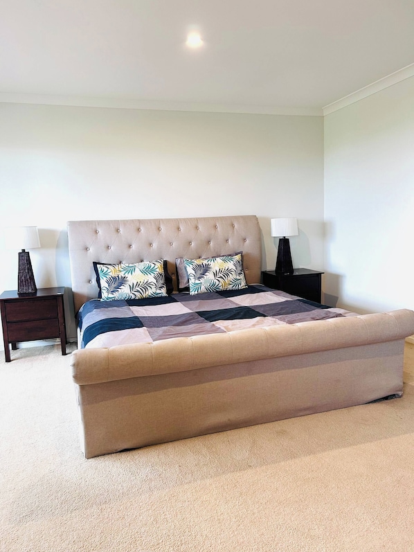 Quarto com cama grande, duas mesas de cabeceira e uma luminária no teto.