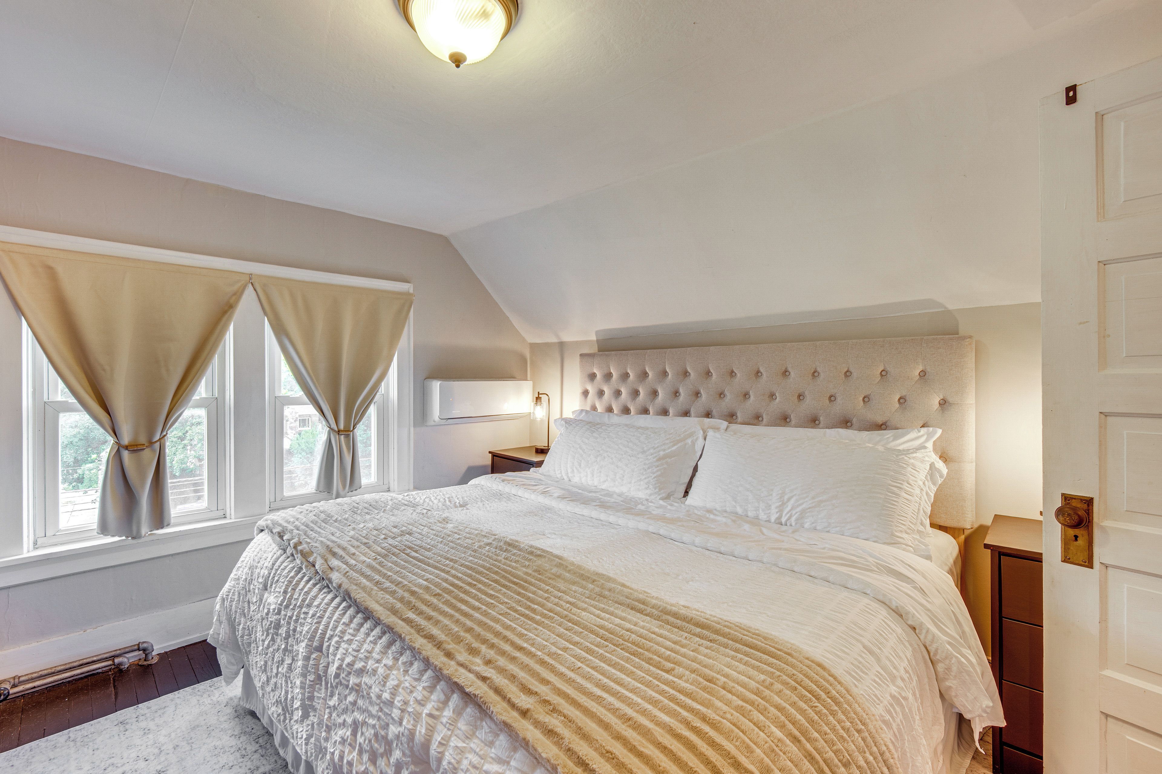 Une chambre à coucher avec un grand lit, une table de chevet, une lampe et une porte.