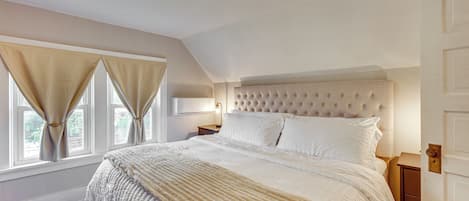 Ein Schlafzimmer mit einem großen Bett, einem Nachttisch, einer Lampe und einer Tür.