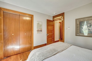 Un dormitorio con cama, armario de madera, un cuadro y un espejo.